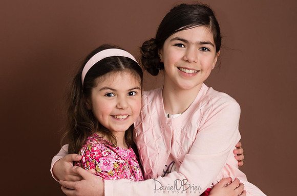 Girls-Sisters-Brown-Background-Smiling