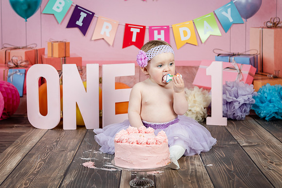 baby-eating-her-birthday-cake-with-pink-background